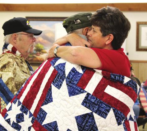 Full of emotion, Debbie Stubbs wraps a veteran in a Quilt of Valor and hugs him as she tells him thank you and welcome home. Ashley Barner | Meridian Tribune