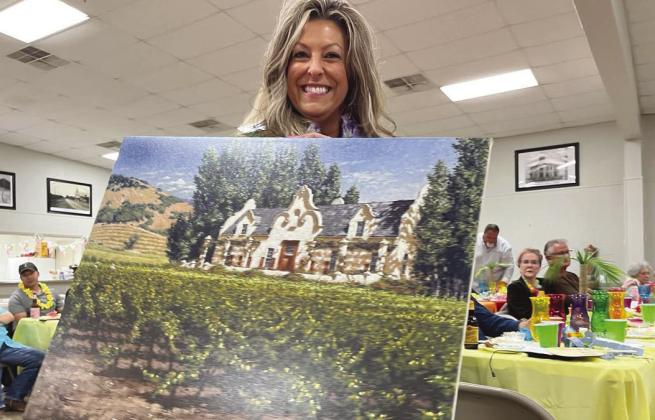 Meridian Public Library board member Kate Brasfield displays a George Hallmark painting during the Jewels and Jeans Fundraiser for the library at the Meridian Civic Center on Saturday night, April 20. Nathan Diebenow | Meridian Tribune