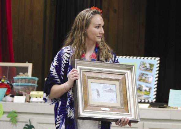 Meridian Public Library board member Darci Allen displays a George Hallmark painting during the Jewels and Jeans Fundraiser for the library at the Meridian Civic Center on Saturday night, April 20. Nathan Diebenow | Meridian Tribune