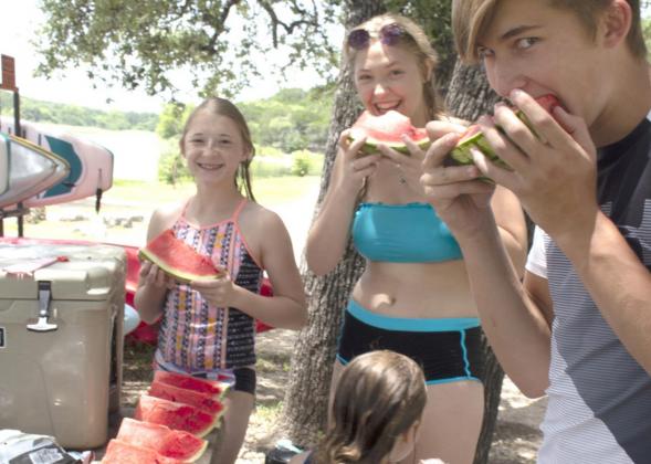 Right, Xavi Smith, Sablra Smith, Gauge Chandler and Landry Chandler eat watermelon for lunch after taking a break from swimming.